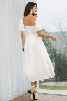 En linje plissert liten hvit kjole med puff ermer